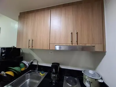 a kitchen with a sink and wooden cabinets at StaycationPH in Manila