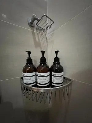 a rack with four bottles of soap in a bathroom at 1BR - Uptown BGC Taguig in Manila