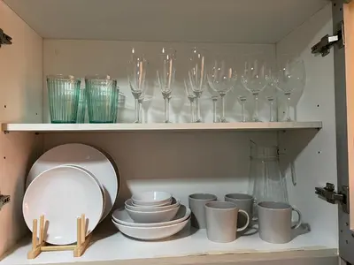 a shelf with wine glasses and plates and bowls at 1BR - Uptown BGC Taguig in Manila
