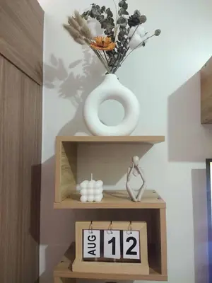 a vase sitting on a wooden shelf with a clock at Red Residences Modern Apartment with City View in Makati in Manila