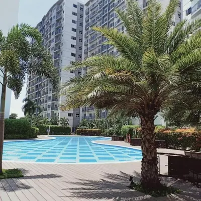 a palm tree in front of a large building at Comfy Studio near Southmall Las Piñas in Manila