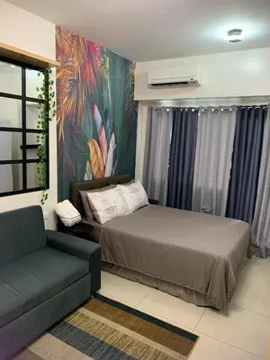 a bedroom with a bed and a couch and a painting at Comfy Studio near Southmall Las Piñas in Manila