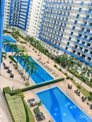 an aerial view of a large building with blue pools at Staycation 2 Bedroom at Sea Residences Pasay across Mall of Asia near NAIA Airport in Manila