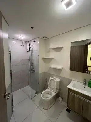 a bathroom with a shower and a toilet and a sink at Cozy Modern Apartment with Luxury Amenities in Manila