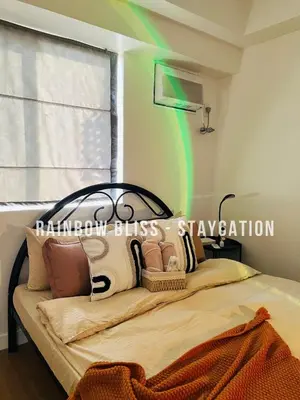 a bedroom with a bed with a green beam at Staycation in Likha in Manila