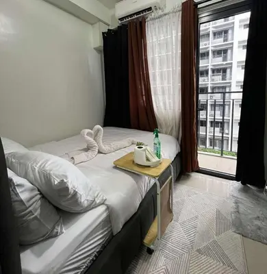 a room with two twin beds with a table and a window at Cozy Haven in Manila