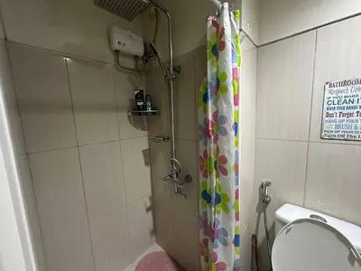 a bathroom with a shower with a toilet and a shower curtain at Simple Pasay Getaway - Entire Apartment for Rent in Manila
