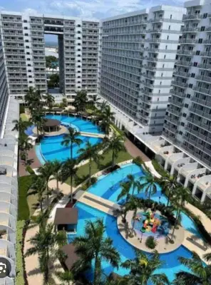 an aerial view of two pools with palm trees and buildings at Charming 1-Bedroom Apartment in the Heart of Pasay City in Manila