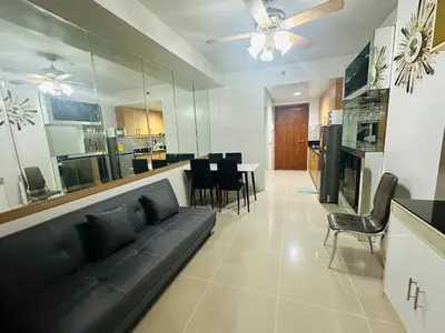 a living room with a black couch and a kitchen at Ultra Pasay City Apartment for Rent - Perfect for Short-Term Stay Front of MOA in Manila