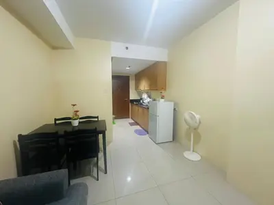 a living room with a table and a kitchen at Timeless Pasay City Apartment for Rent in Manila