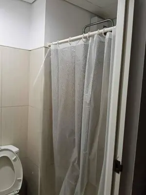 a bathroom with a shower curtain and a toilet at Gentle Pasay City Apartment for Rent - Perfect Family Getaway Near Mall of Asia in Manila