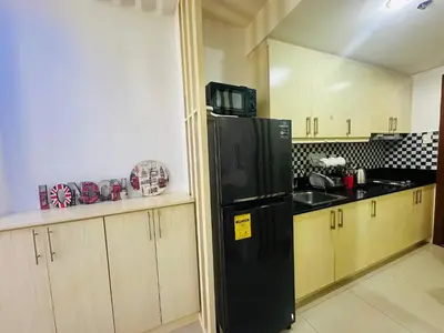 a kitchen with a black refrigerator and wooden cabinets at Xenial Pasay City Apartment for Rent - Entire House Front of Mall of Asia in Manila