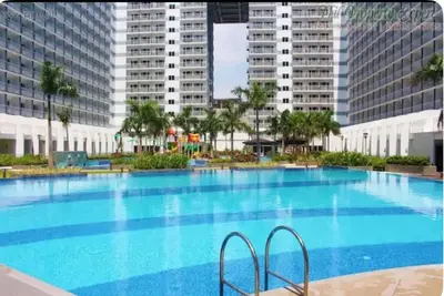a large swimming pool with tall buildings in the background at Quaint 2BR Connected Apartment in Pasay City - Perfect for Families front of MOA in Manila