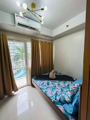 a bedroom with a bed and a large window at Vibrant Pasay City Apartment for Rent - Perfect Home Base front of Mall of Asia in Manila