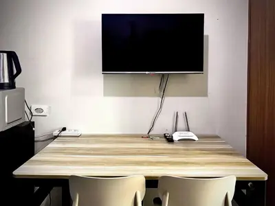 a wooden table with chairs and a television on a wall at Kempt Pasay City Apartment for Rent - Perfect for Short-Term Stay front of MOA in Manila
