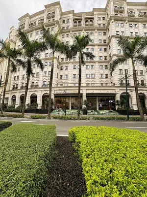 a large white building with palm trees in front of it at Kai cabins WALKING DISTANCE NAIA 3 AIRPORT NEWPORT CITY in Manila