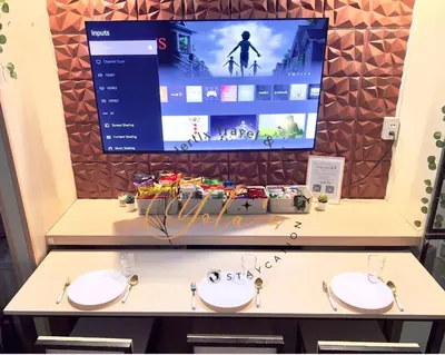a tv screen in a room with two sinks at Yola's Staycation - Jazz Residences Makati City in Manila