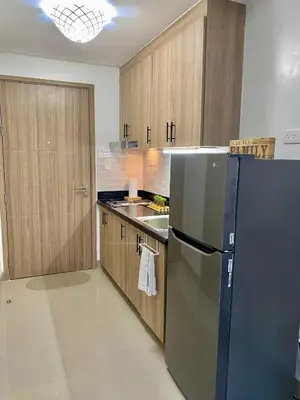 a kitchen with a black refrigerator and wooden cabinets at Cordial Condo in Manila