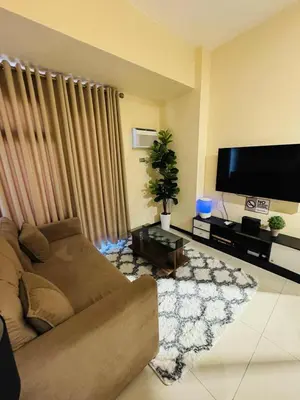 a living room with a couch and a flat screen tv at 1-Bedroom Condo - Stunning Sunset at the City in Manila