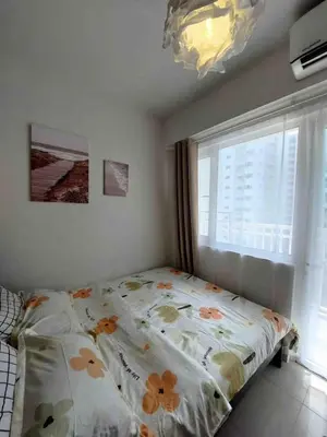 a bedroom with a bed with a floweridered comforter and a window at Staycation in Marymount in Manila