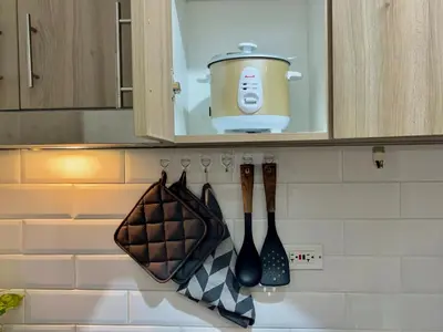 a kitchen counter with utensils hanging from a cabinet at Liwayway Suites in Manila
