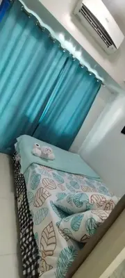 a bed in a room with a blue curtain at Sea Residences Staycation Near MOA Pasay City by Rose in Manila