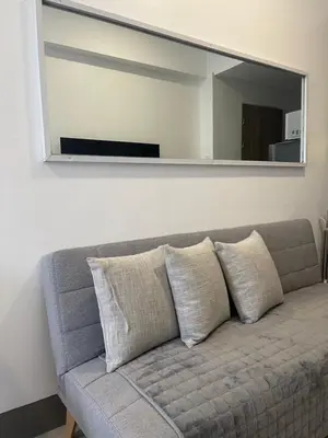 a couch in a living room with a mirror at FAME Residences - The 37th Suite in Manila