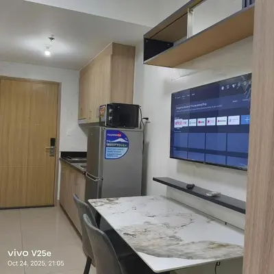 a kitchen with a table and a refrigerator and a tv at shore 2 residences admin in Manila