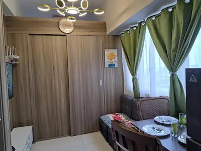 a dining room with a table and a chandelier at Gavinne Place Coast Residences in Manila