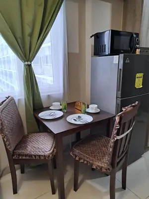 a kitchen table with two chairs and a refrigerator at Gavinne Place Coast Residences in Manila