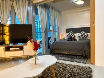 a bedroom with a bed and a tv and a table at BGC Premium 1BR with Balcony fast 600 mbps Fibre in Manila