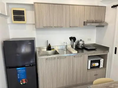 a kitchen with a black refrigerator and a sink at 3BR golf view in fort victoria BGC in Manila