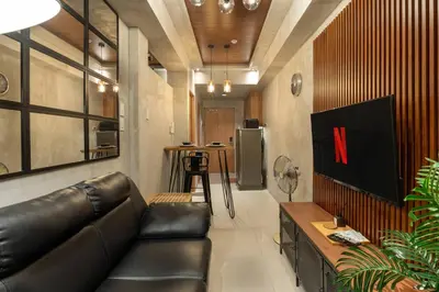 a living room with a black leather couch and a bar at Modern Industrial 1 BR | Condo | MOA Shore 3 NAIA in Manila
