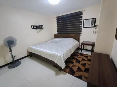 a bedroom with a bed and a desk and a fan at David home in Manila