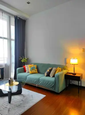 a living room with a green couch with pillows on it at Big NEW 1 Bedroom corner unit with Balconies - FREE Sauna Pool Gym View of Skyline, Manila Bay, Sunset in Manila