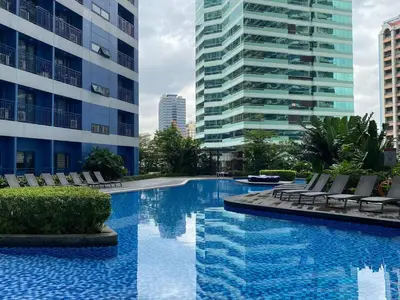 a swimming pool with chairs and a building at Air Residences 46F Stunning View Wifi & Netflix in Manila