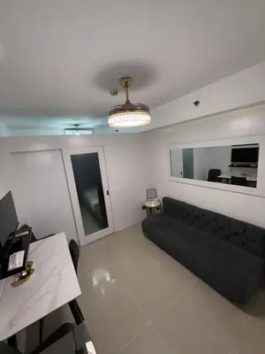 a living room with a black couch and a mirror at Staycation By ABBYBI in Manila