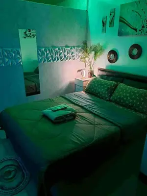 a bedroom with a green bed with a light on it at Staycation at Brgy Cupang in Manila