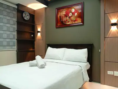 a bedroom with a white bed with a clock on the wall at Cozy Manila Condo Retreat with Shared Pool in Manila