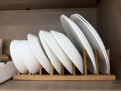 a group of white plates on a wooden shelf at Cami Haus at Fame Residences in Manila
