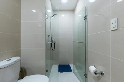 a bathroom with a glass shower with a toilet at Amazing View - Cozy 1BR at One Eastwood with Washer High Speed Wi-Fi in Manila
