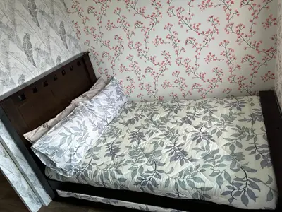 a small bed in a bedroom with floral wallpaper at Family Condo SMB in Manila