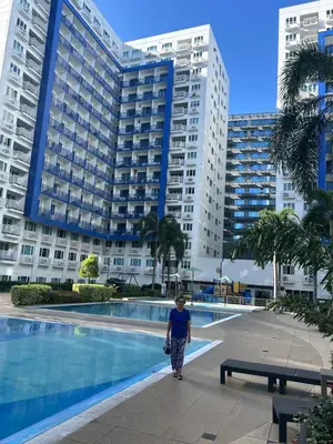 a woman walking in front of a large building at Family Condo SMB in Manila