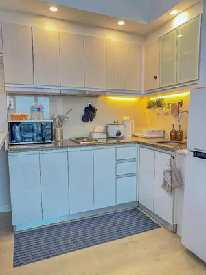 a kitchen with white cabinets and a white refrigerator at nJoy! Elegant Peach Heaven at Venice Grand Canal in Manila