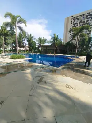 a swimming pool with palm trees and a building at Staycation in Brgy Cupang in Manila