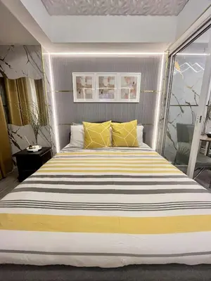 a bedroom with a large bed with yellow and white pillows at Azure Staycation by Cm in Manila