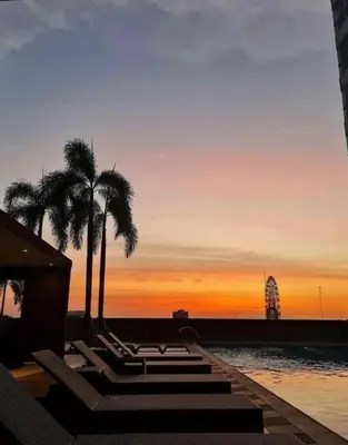 a sunset with palm trees and a swimming pool at Smdc Breeze Residences-The Metro Breeze-Staycation in Manila