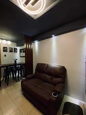 a living room with a brown couch and a table at Staycation in Brgy Buli in Manila
