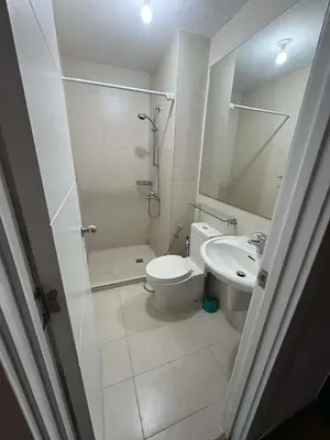 a bathroom with a toilet and a shower and a sink at Staycation at Brgy Sucat in Manila
