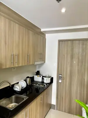 a kitchen with wooden cabinets and a sink and a door at Fame Residence Tower 4 near Greenfield and Shaw MRT in Sampong